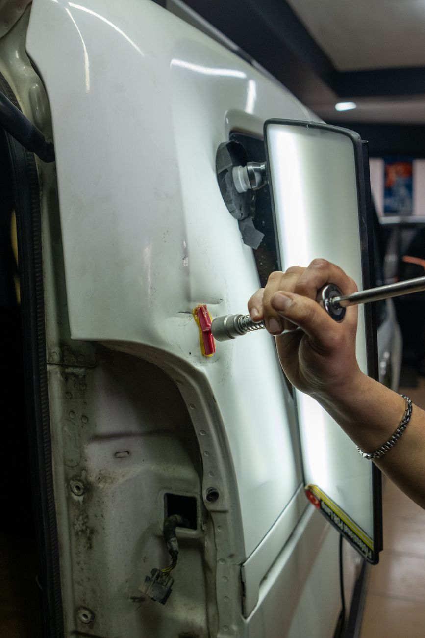 Technician repairing a dent in a car panel
